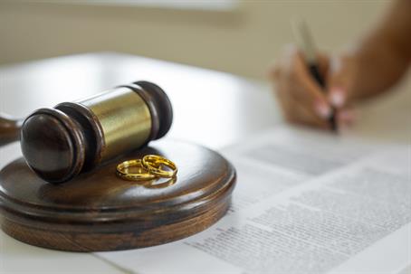 Wedding rings and gavel with a person signing a contract